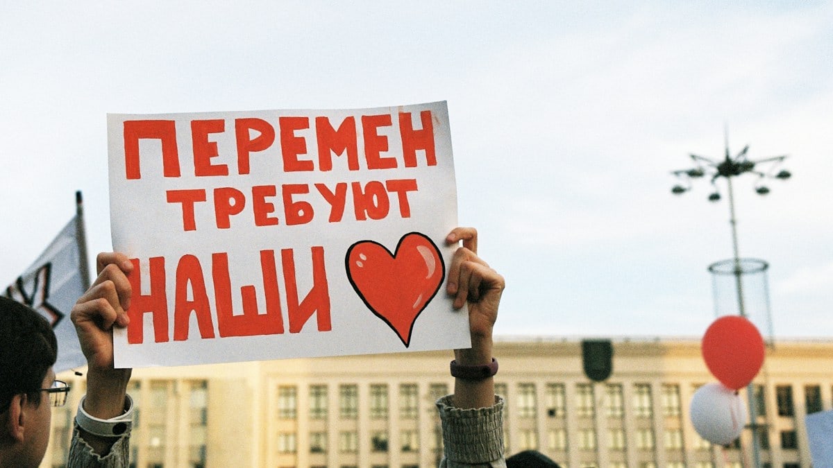 person holding red and white love is love print board